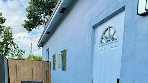 Un cortile con erba sintetica verde, una porta bianca e una recinzione in legno.