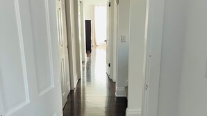 A hallway with white doors and dark wooden flooring.