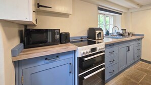 A kitchen with a microwave, toaster, and oven, a window with a view, and blue cabinets. - 2 bedroom accommodation in Aldwark, near Brassington (Aldwark, near Brassington)