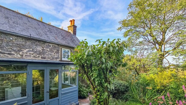 A stone house with a grey roof, a chimney, and a garden with various plants and flowers. - 2 bedroom accommodation in Aldwark, near Brassington (Aldwark, near Brassington)