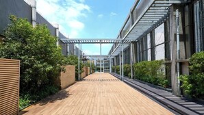 A wooden pathway leading to a covered area with metal railings and greenery on both sides. - Starry Four Sea Hotel (Foshan)