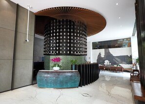 A lobby with a central column, seating area, and a reception desk. - Starry Four Sea Hotel (Foshan)