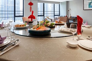 A dining table set with various dishes, glasses, and cutlery, with a cityscape view through large windows. - Starry Four Sea Hotel (Foshan)