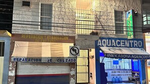 Um edifício com uma placa indicando os serviços de 'REPARACION E CALZADO' e 'AQUACENTRO'.