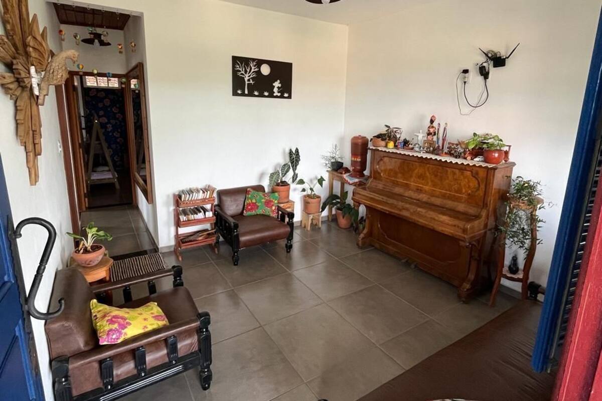Ein Wohnzimmer mit einem Klavier, Sofas und Topfpflanzen.