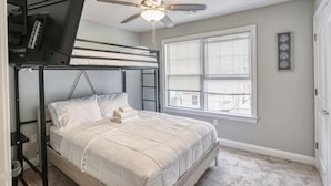 A bedroom with a bunk bed, a ceiling fan, a window with blinds, and a small desk with a computer. - Waterfront Escape! NYC Ferry, Beach, Modern New Construction 3 bedroom 3 bath (Highlands)