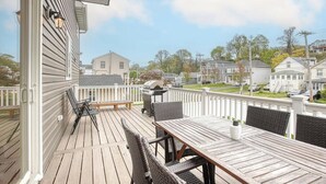 A wooden deck with outdoor furniture, a grill, and a view of a residential neighborhood. - Waterfront Escape! NYC Ferry, Beach, Modern New Construction 3 bedroom 3 bath (Highlands)