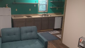 A compact kitchen with a built-in refrigerator, a sink, and a dishwasher. There is a blue sofa in the foreground and a window with a view of trees. - HICKORY HIDEOUT
The cabin is surrounded by a large area of trees for privacy (Mena)