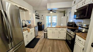 A modern kitchen with stainless steel appliances, white cabinetry, and a central island. - Memphis Retreat w/ Sunroom, Pool Table, Retro Gaming, Gym & Relaxing Vibe (Memphis)
