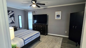 A bedroom with a bed, a TV, a ceiling fan, and a dark wardrobe. - Memphis Retreat w/ Sunroom, Pool Table, Retro Gaming, Gym & Relaxing Vibe (Memphis)