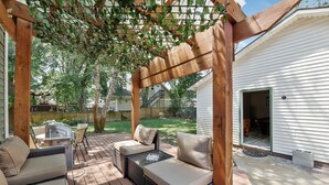 En overdækket terrasse med fletmøbler og en pergola.