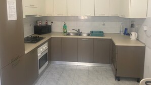 A compact kitchen with a gas stove, microwave, sink, and cabinets.