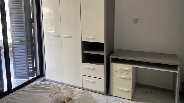 A bedroom with a bed, a wardrobe, and a desk.