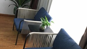 Et værelse med to stole, et lille bord med en plante og en potteplante i hjørnet.