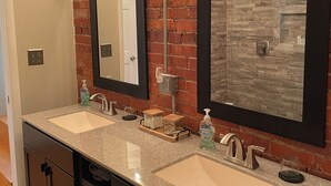 Une salle de bain avec deux lavabos, un miroir et un ventilateur.