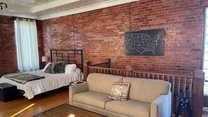 Une pièce avec un mur en briques, un lit, un canapé et une table basse.