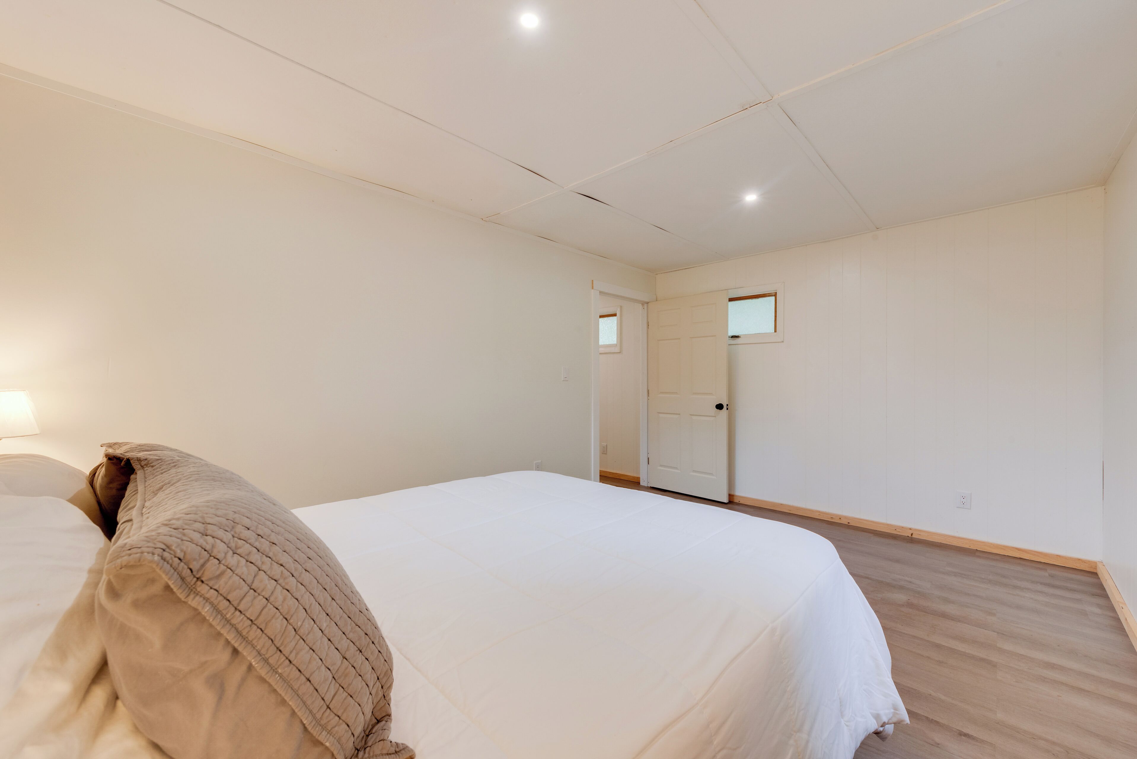 A bedroom with a bed, a door, and a light switch on the wall.