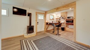 A cozy living room with a fireplace, a TV mounted on the wall, and a kitchen area with wooden cabinets and a microwave. - Shared Perks: Deluxe Cabin B at Elk Creek Escape! (Hillsgrove)