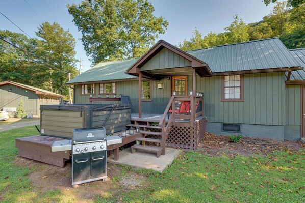 Cozy cabin with a front deck, wooden staircase, and two grills.