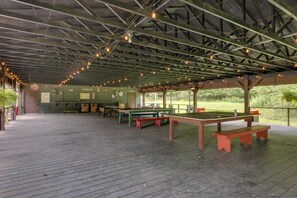 Enjoy dining and socializing in this charming pavilion with picnic tables and benches under a rustic structure with exposed beams and string lights.