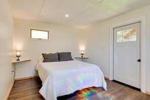 Een slaapkamer met een bed, twee nachtkastjes, een deur en een raam.