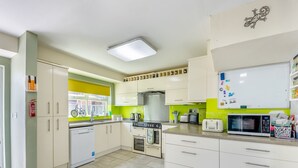 Una cocina con armarios blancos, un microondas, una estufa y un lavaplatos.