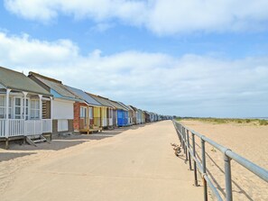 Eine Reihe von Strandhütten mit einem Sandweg, der zum Strand führt.