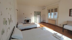 Un'ampia camera da letto con due letti, una scrivania e un termosifone.