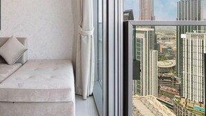 Una habitación moderna con un ventanal grande, un sofá y vistas del Burj Khalifa.