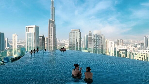 Una piscina infinita en la azotea con un horizonte urbano y el Burj Khalifa al fondo.