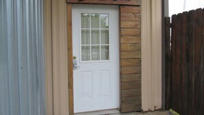 A white door with a window, set in a wooden frame, with a metal fence to the right. - Cozy 2-bedroom cabin in front of the lake!!! (Mannford)