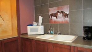 A kitchen with a microwave, sink, and coffee maker. - Cozy 2-bedroom cabin in front of the lake!!! (Mannford)