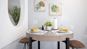 A dining area with a round table, two chairs, a potted plant, and two framed botanical prints on the wall. - 𖡡 First Street Flat - 1BR Apt just 15 Min to NYC (Hoboken)