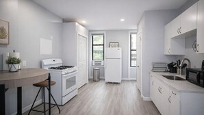 A modern kitchen with white cabinetry, a gas stove, a refrigerator, and a sink. - 𖡡 First Street Flat - 1BR Apt just 15 Min to NYC (Hoboken)