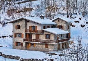 A multi-story stone building with a balcony, surrounded by snow-covered trees. - Casa-Tour du Merle N° 2 (Champagny-en-Vanoise)