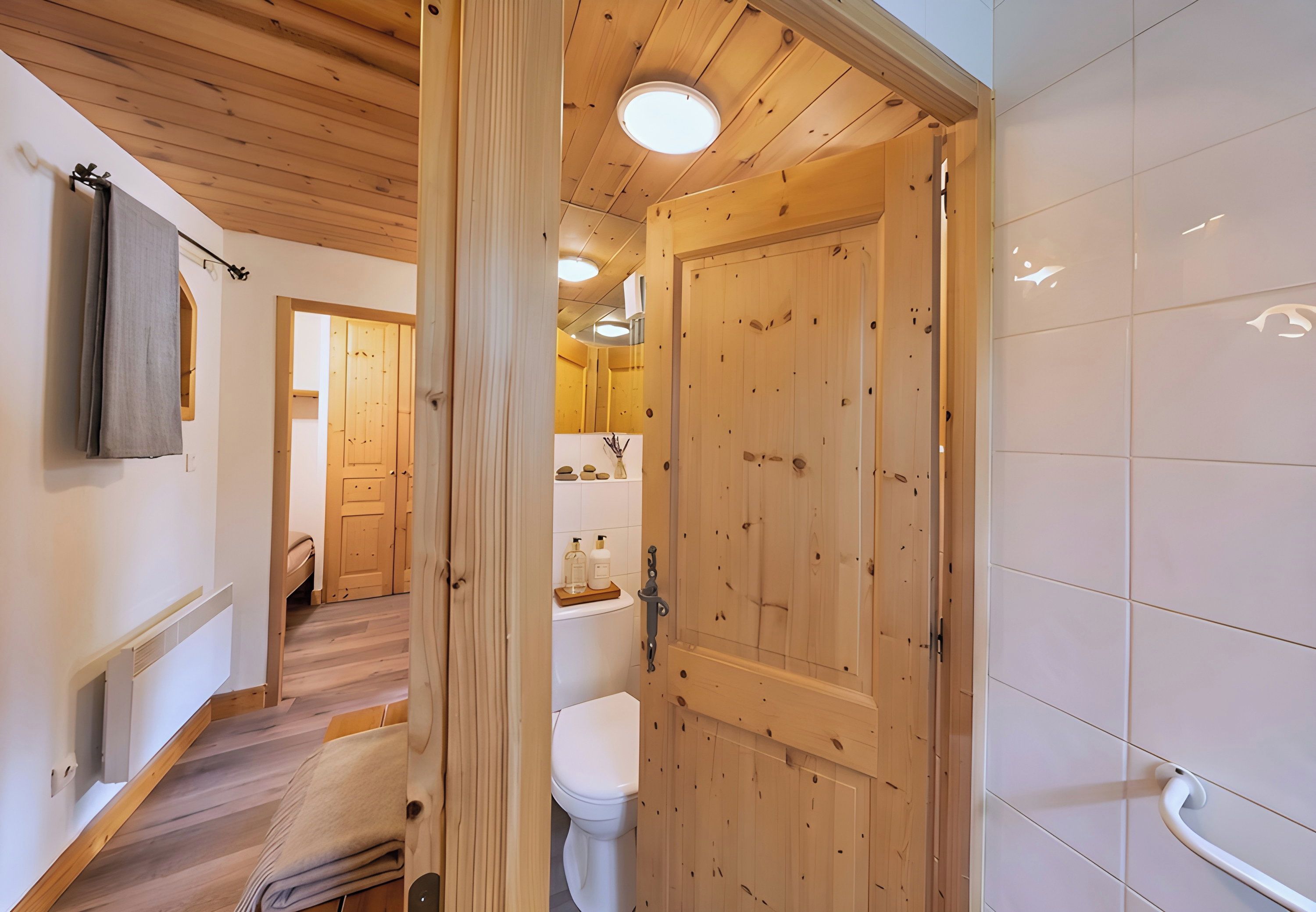 Ein Badezimmer mit Holzwandverkleidung, einer Toilette, einem Handtuchhalter und einer Duschkabine.
