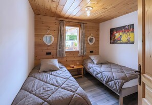 A room with two beds, a small table, a window with curtains, and a painting on the wall. - Casa-Tour du Merle N° 2 (Champagny-en-Vanoise)