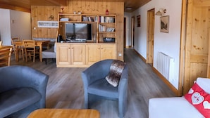 Un interior de madera con televisor, estanterías, comedor y sofá.
