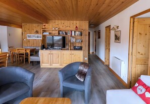Un intérieur en bois comprenant un téléviseur, des étagères, un coin repas et un canapé.