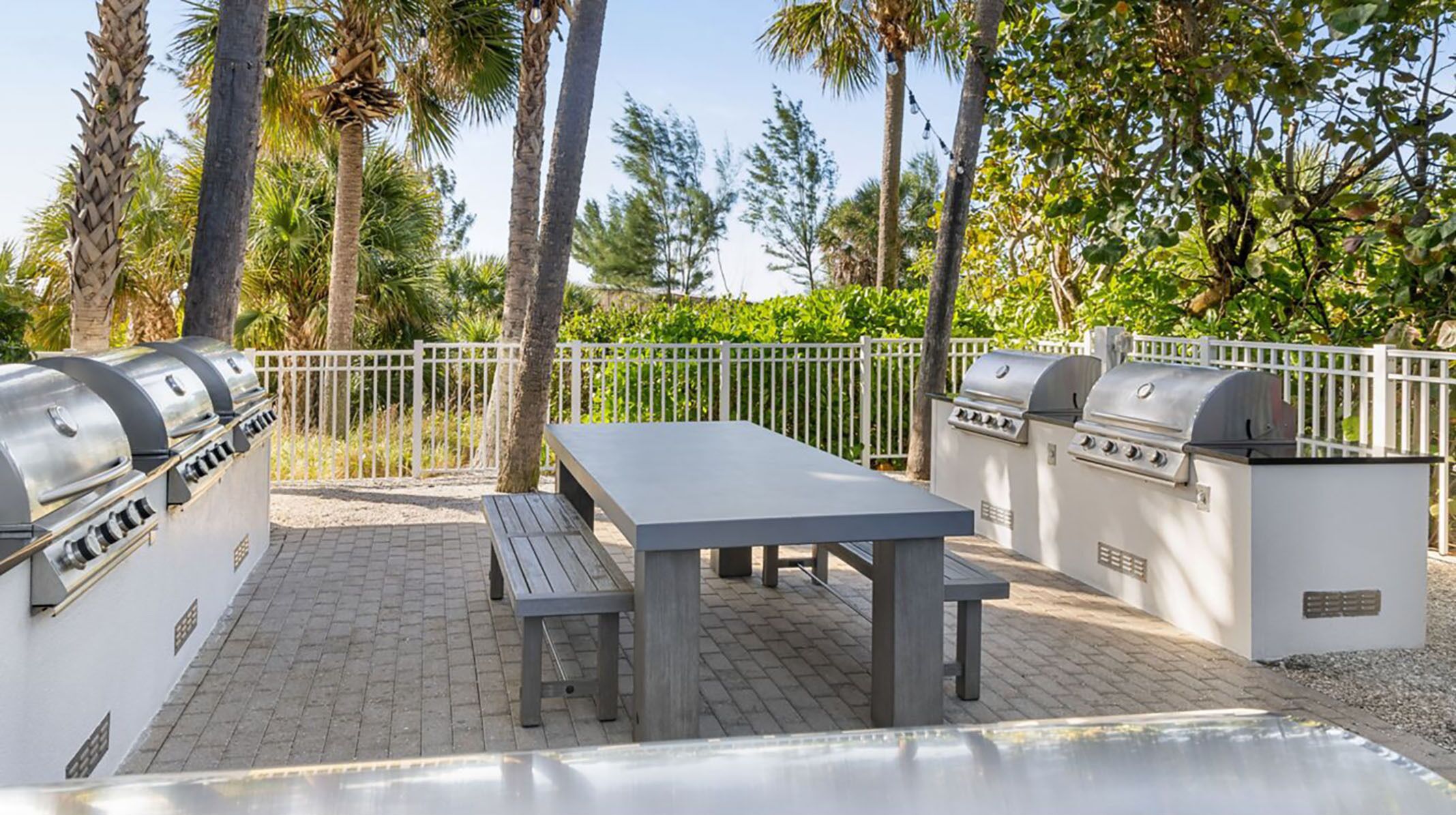 An outdoor patio with a barbecue grill, a table, and benches.