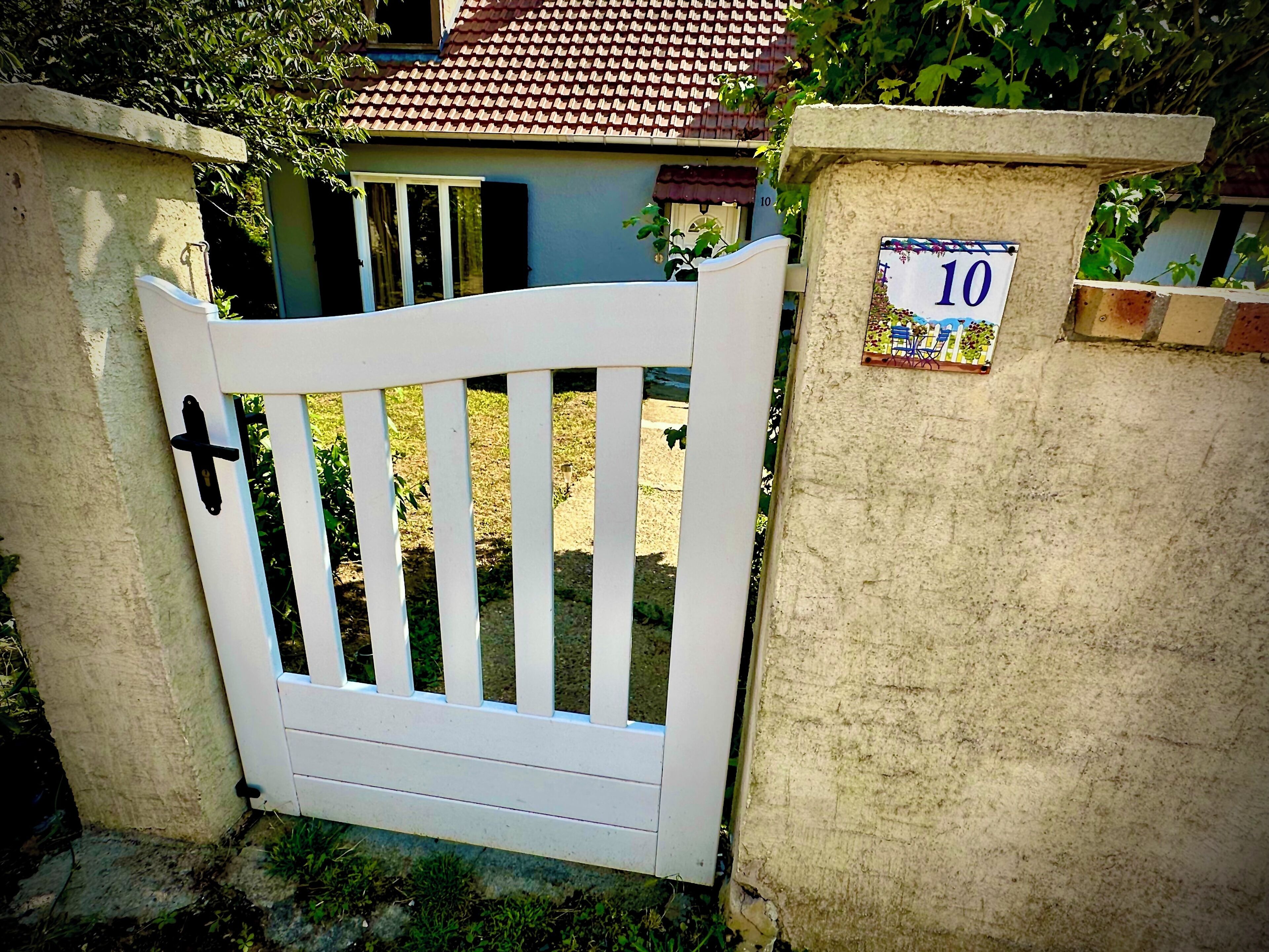 A white gate with a number '10' sign on a concrete wall.