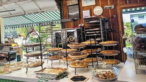 Mostrador de panadería con diversas tartas y pasteles expuestos en soportes metálicos.