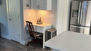 Una cocina moderna con armarios blancos, un refrigerador de acero inoxidable y piso de madera.