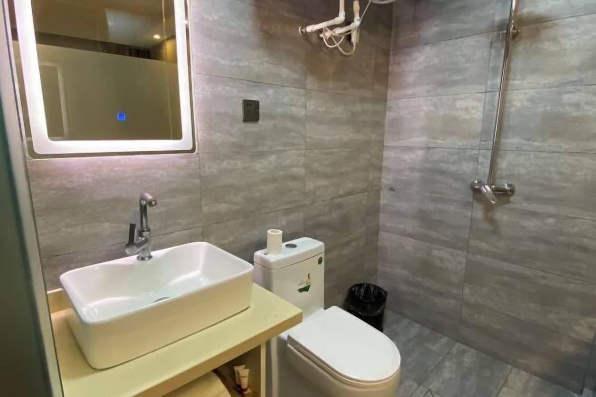 A bathroom with a white sink, toilet, and shower.