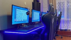 Una configuración de computadora con múltiples monitores, un teclado y sillas gamer.