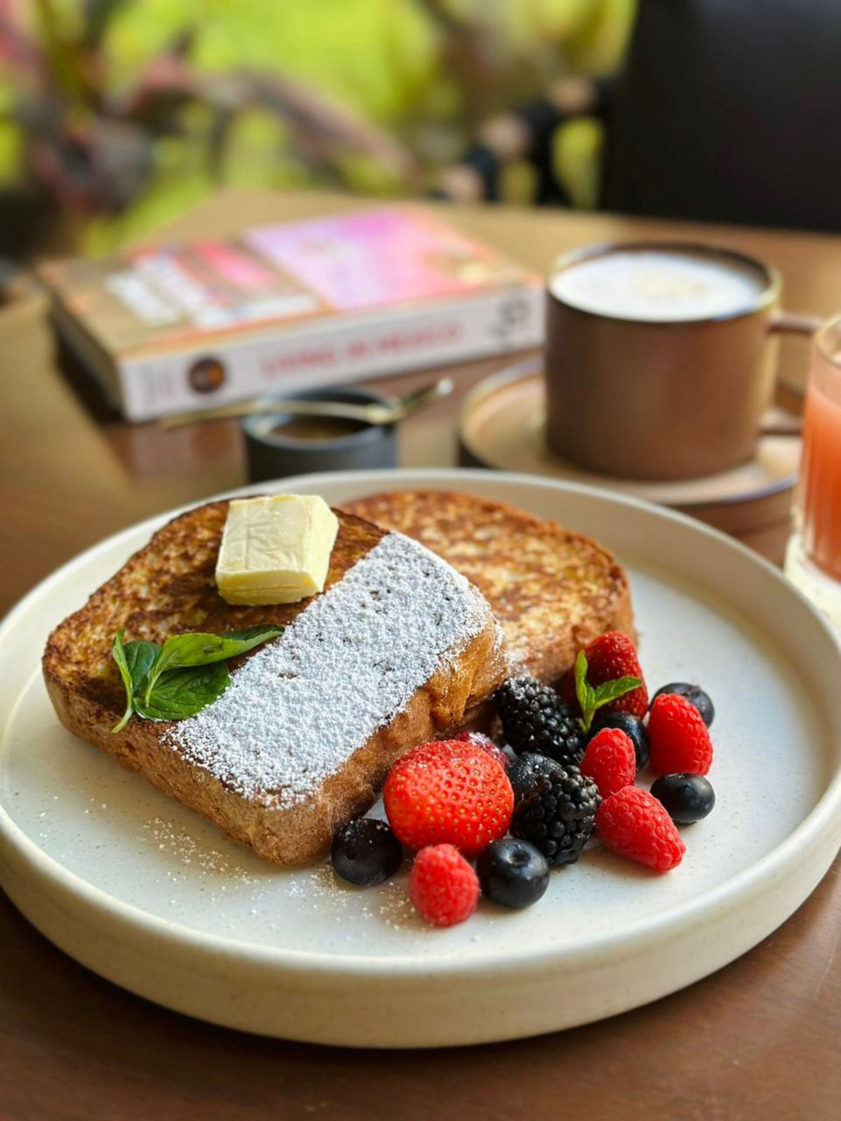A plate of French toast with powdered sugar, a pat of butter, and fresh berries.