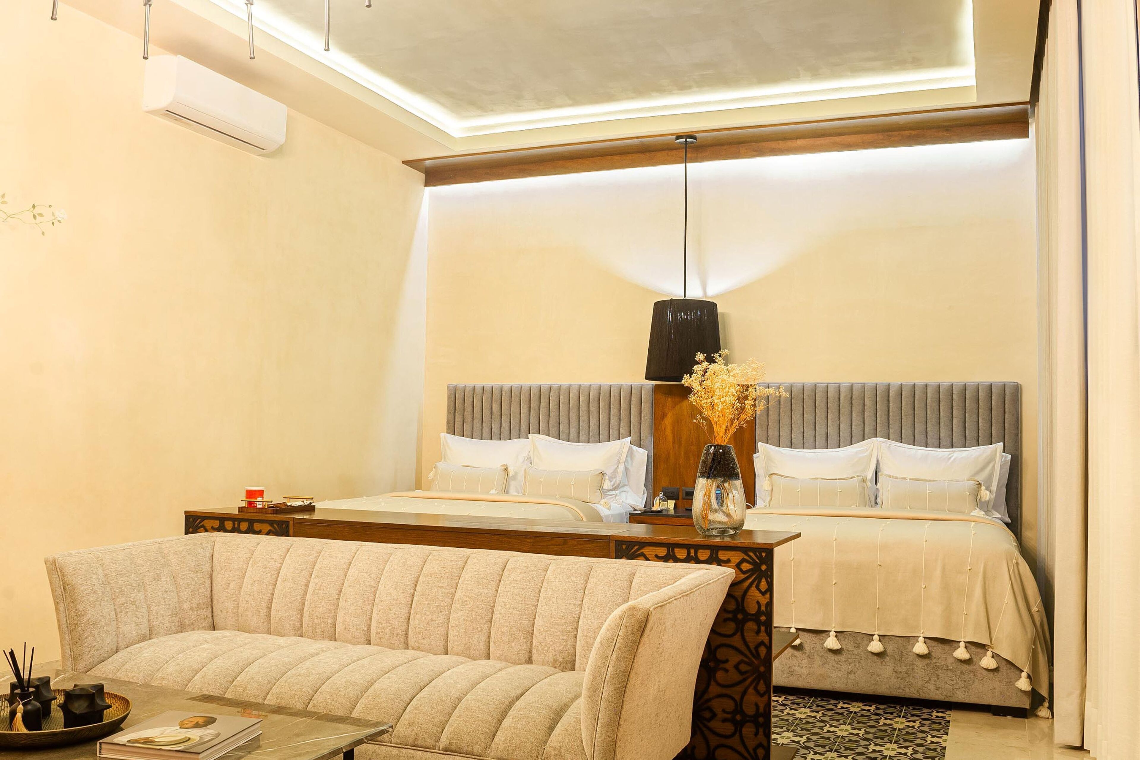 Een slaapkamer met een bed, een slaapbank, een nachtkastje en een hanglamp.