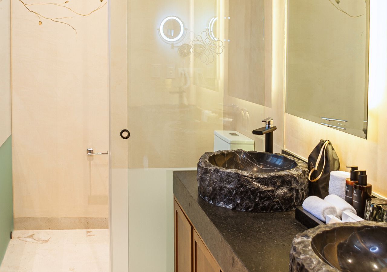 Une salle de bain avec un grand miroir, un lavabo en pierre et un espace douche.