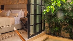 A bedroom with a bed, a nightstand, a wooden chair, and a small table. - Adoro Hotel Boutique (Mérida)