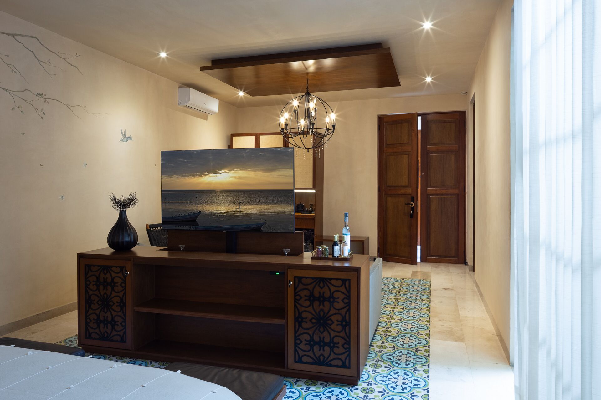 Ein Schlafzimmer mit einem Bett, einem Schreibtisch mit einem Gemälde, einer Chandelüster und einem Kleiderschrank.